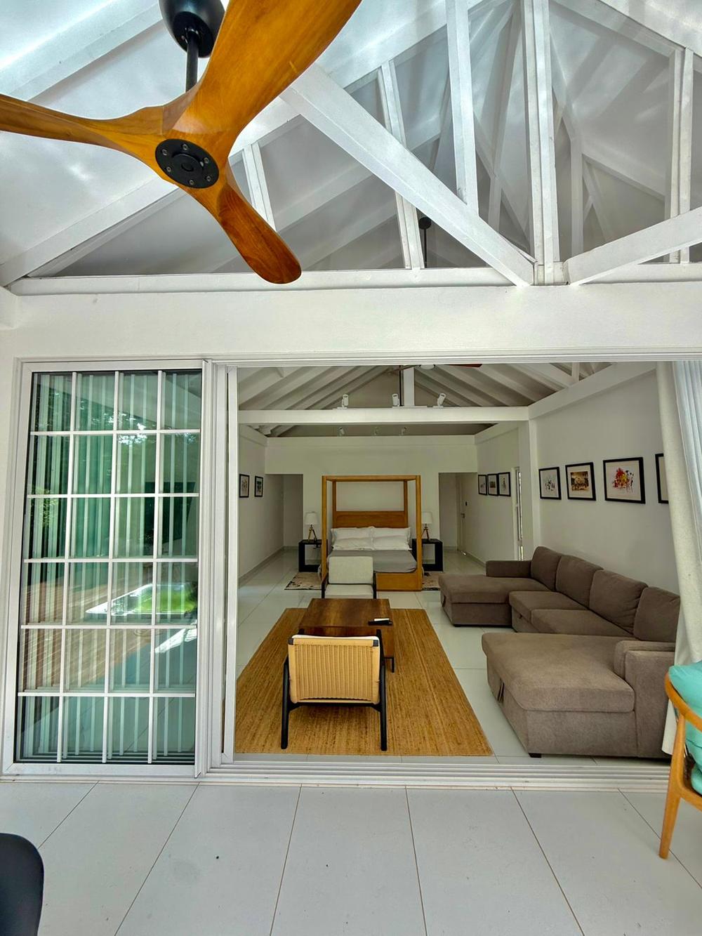 The villa interior — open living and bedroom under vaulted timber ceiling